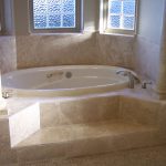 white bathtub surrounded with beige granite