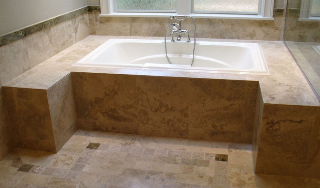 white bathtub surrounded with brown granite