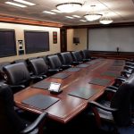 brown conference table surrounded by black office chairs