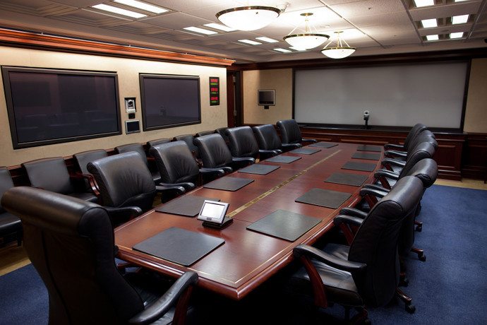 brown conference table surrounded by black office chairs